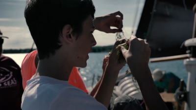 teenagher looking at a specimen on board a boat
