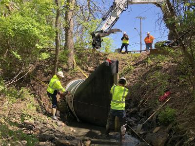 engineers installing a check valve in a pipe in a ravine