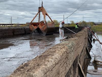 Two people power washing a barge.
