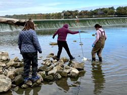 three people standing on rocks in shallow water