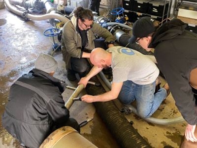 Four staff members perform maintenance on a filter nozzle